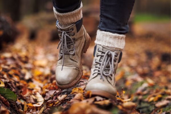 Pessoa caminhando na floresta em cima das folhas na época de Outono.