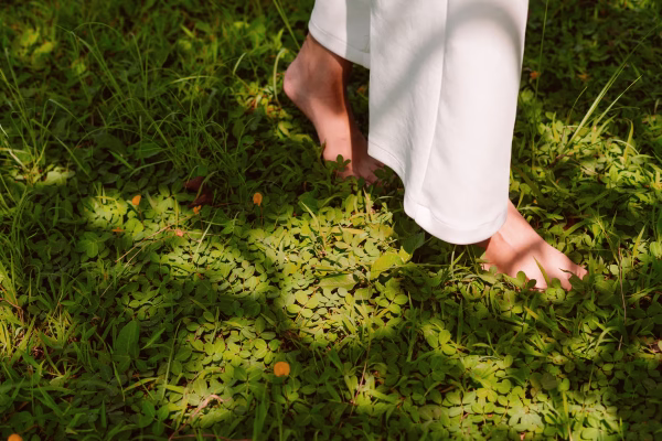 mulher caminhando descalça sob as folhas verdes